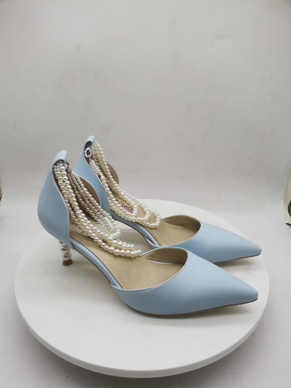 Light blue heeled slingback shoes with white pearl-bead ankle straps and metal heel