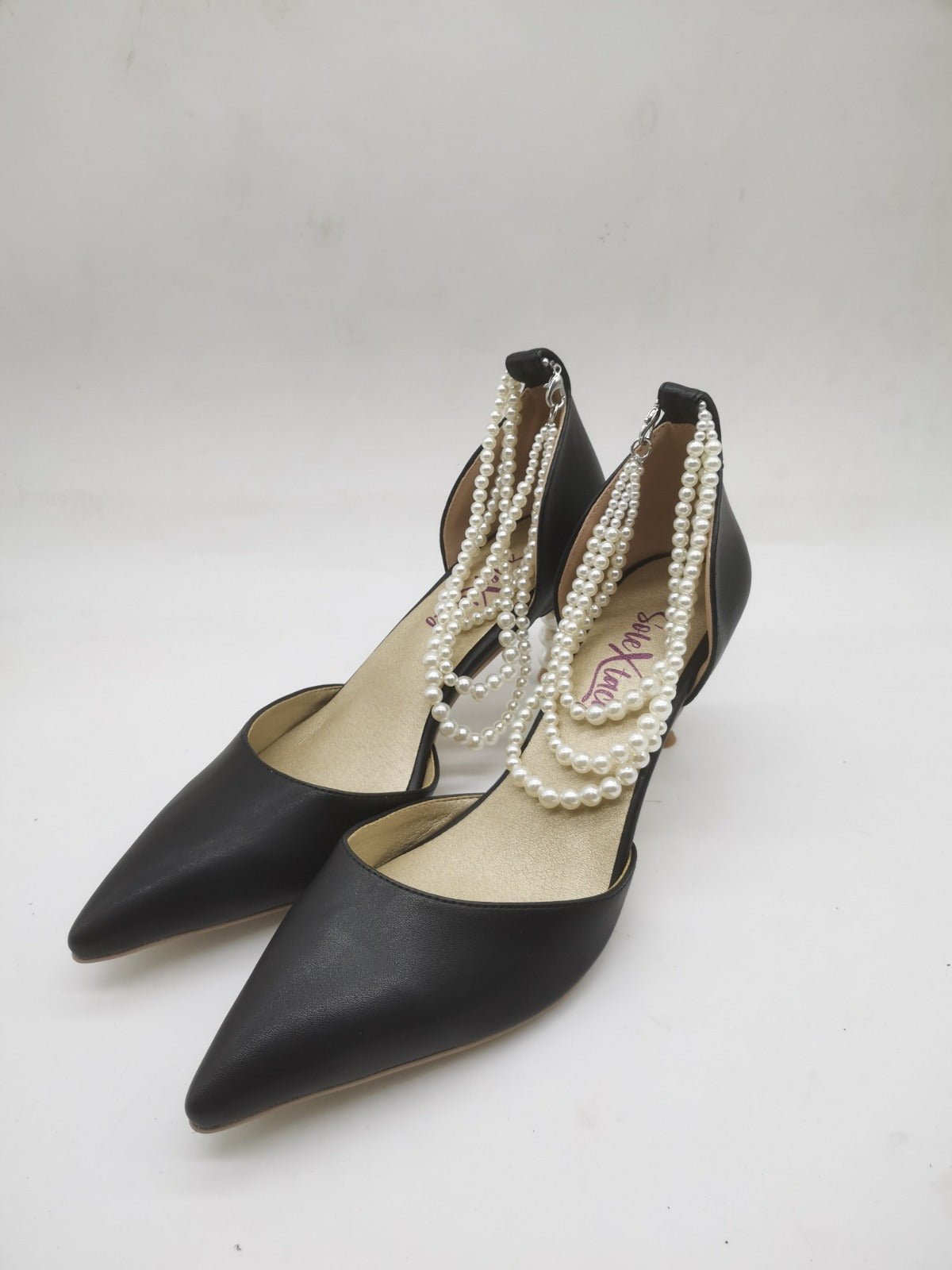 Black pointed heeled pumps with white pearl-bead ankle straps and metal heel