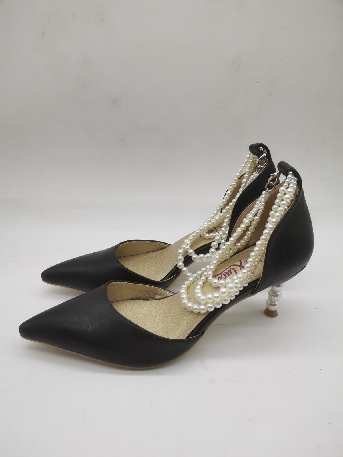 Black pointed-toe pumps with pearl strap and slim heel