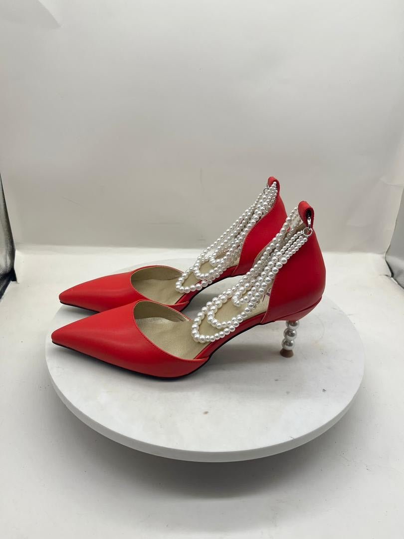 Red heeled slingback shoes with white pearl-bead ankle straps and bow trim