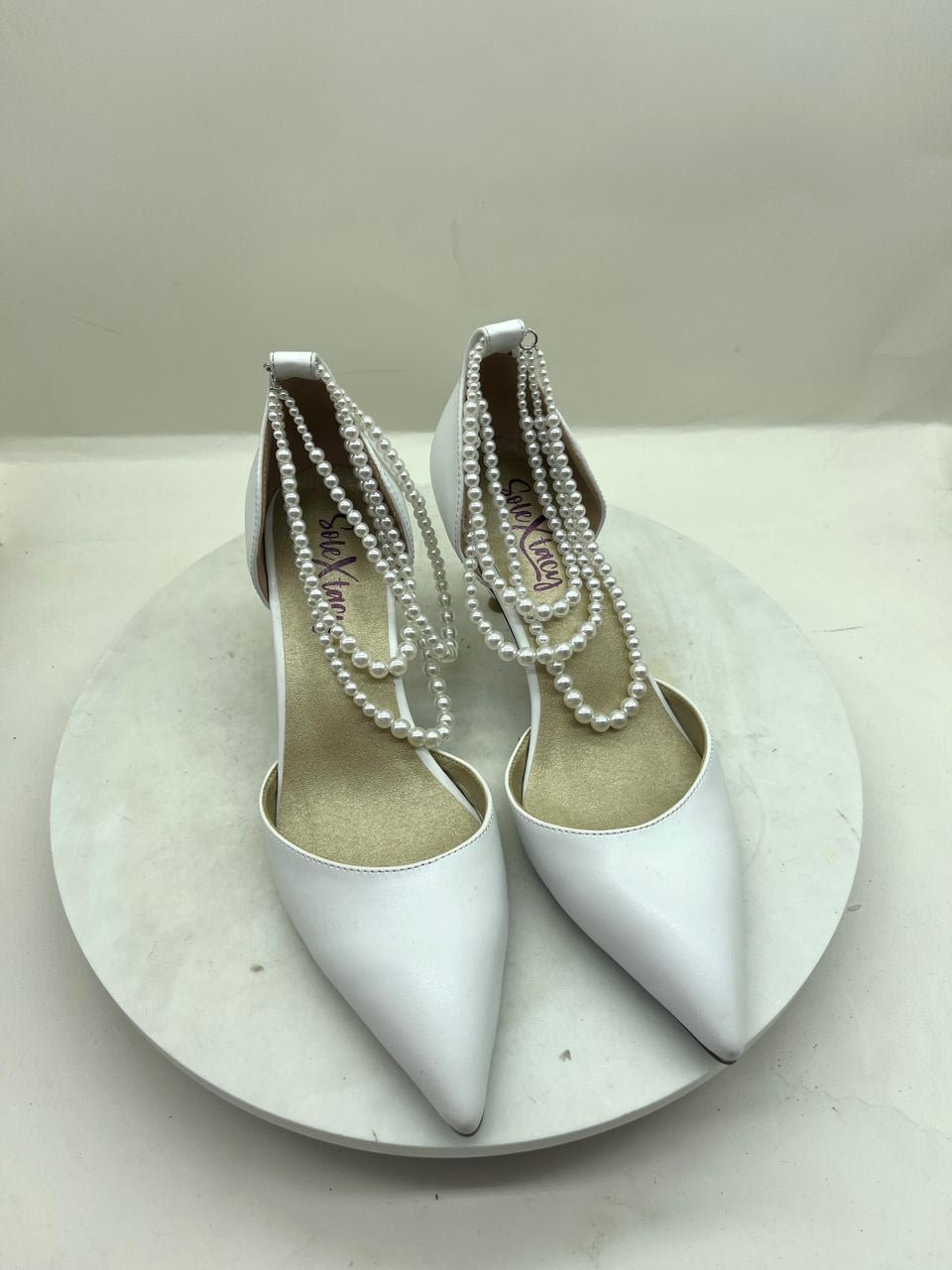 White pointed-toe stiletto pumps with pearl chain trim and double sling straps