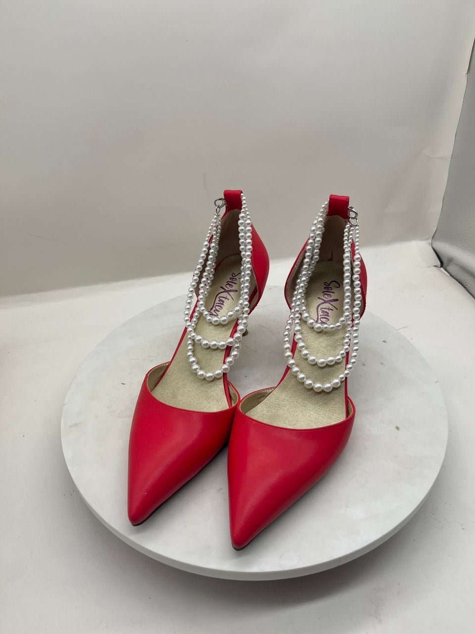Red pointed-toe stiletto pumps with pearl chain trim and double sling straps