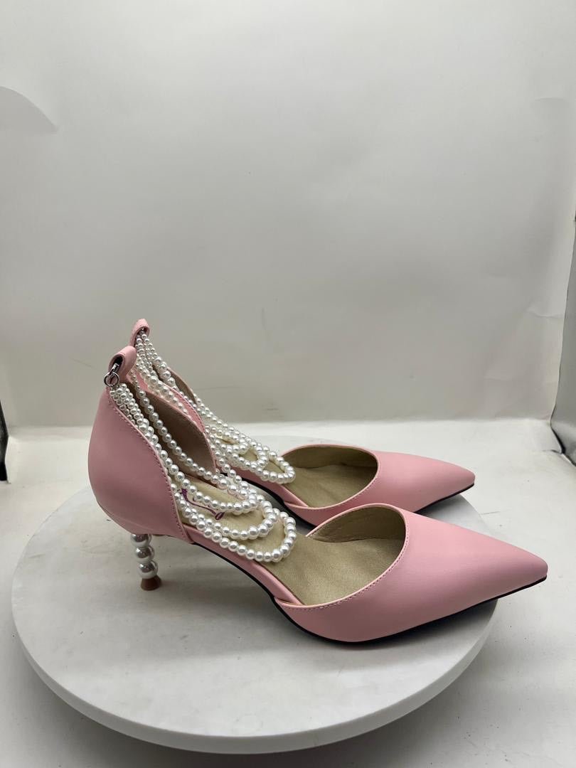 Pink pointed-toe stiletto pumps with pearl chain trim and dangling pearl accents